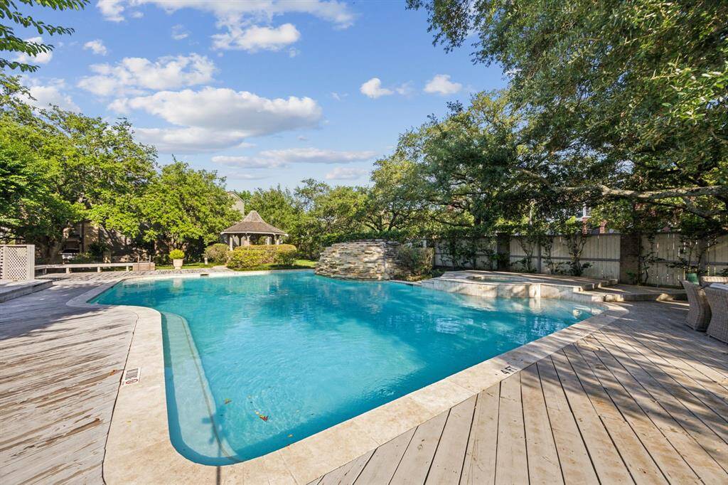 Community pool and hot tub with wooded backdrop.