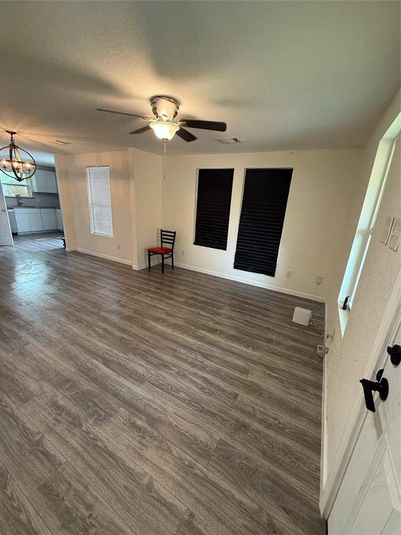 From this vantage point, the living area extends gracefully toward the kitchen, showcasing an open layout that encourages connection. Light filters in through multiple windows, emphasizing the scale of the space.