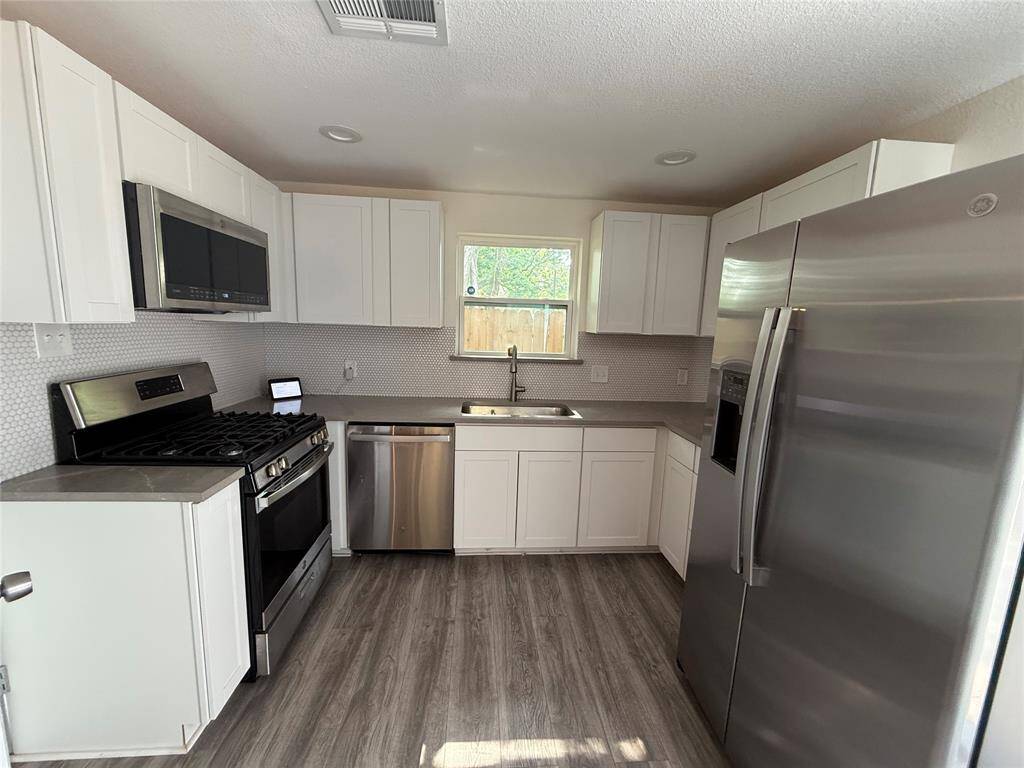 A culinary space that blends function and finesse—abundant white cabinetry offers ample storage, while smooth quartz countertops meet a complementing backsplash. The soft gray tones balance beautifully with crisp white finishes.