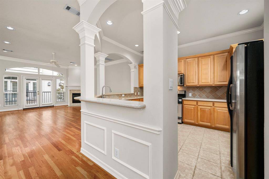 An arched pass-through provides visibility from the kitchen to the living area, promoting easy interaction while entertaining. The blend of tile and hardwood flooring separates the kitchen subtly while keeping the flow open.