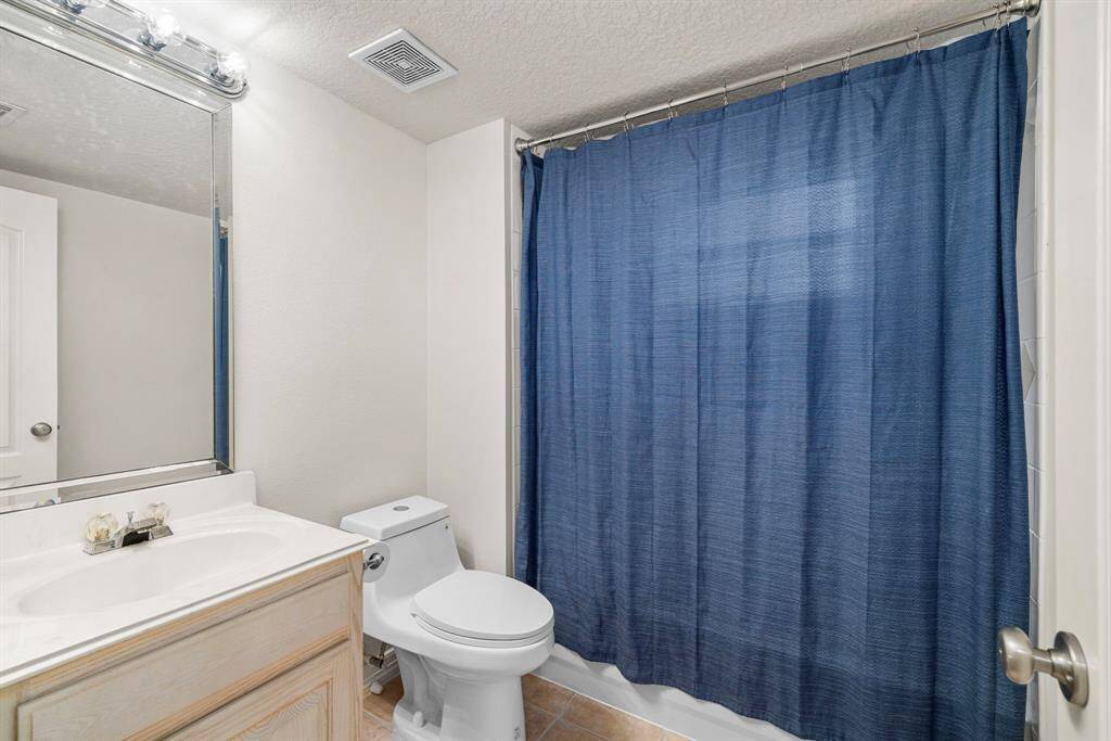 The downstairs full bath offers a practical layout with a shower/tub combination, large mirror, and ample countertop space. Its neutral tones create a clean and inviting atmosphere.