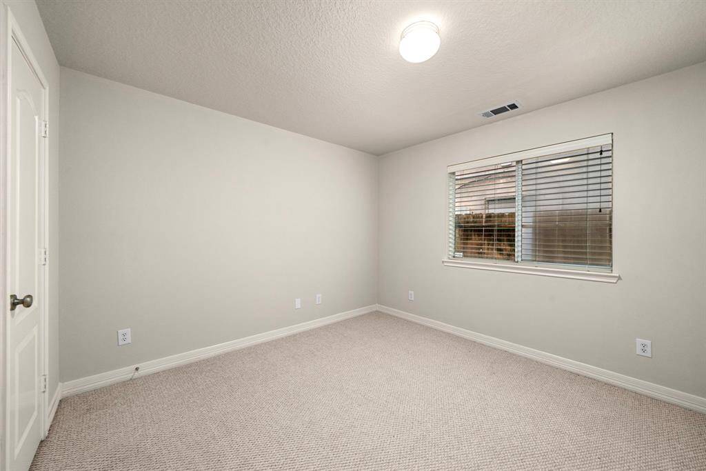 One of the secondary bedrooms, complete with soft carpeting, a large window, and a closet, offering privacy and comfort. Ideal for a guest room, child’s room, or office setup.