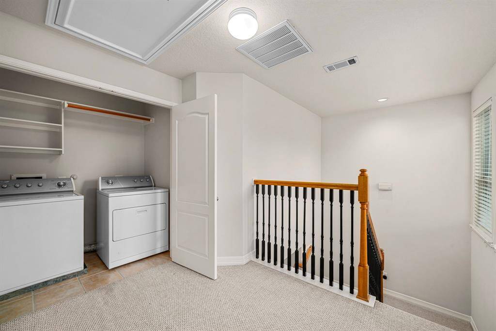 Convenient upstairs laundry area with side-by-side washer and dryer, open shelving, and hanging rod. Located off the landing, it provides practical use of space without sacrificing functionality.