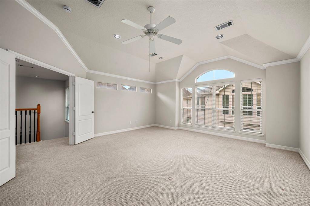 A wide-angle look at the primary bedroom emphasizes its generous proportions and architectural ceiling design. It connects effortlessly to both the bathroom and hallway.