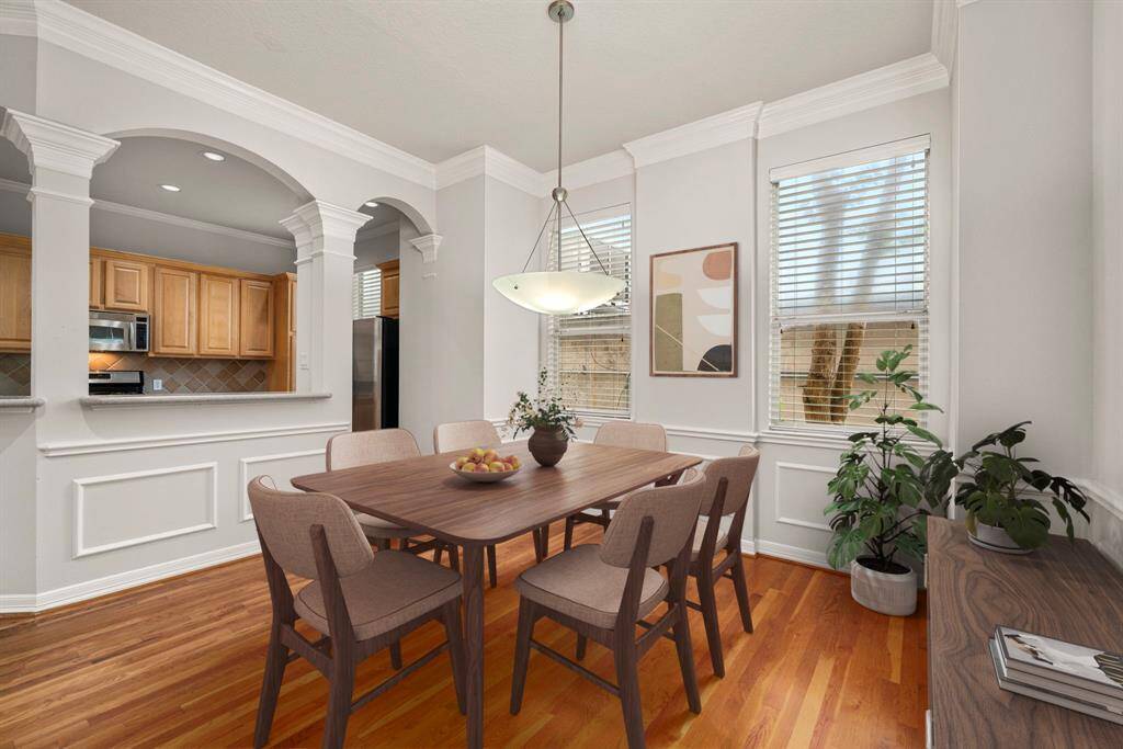 **Virtually Staged**The elegant dining area is framed by wainscoting and crown molding, offering a timeless setting for casual meals or formal dinners. Large windows bring in natural light and overlook the private side of the home.