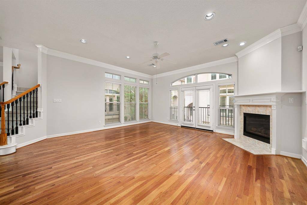 The spacious living area features soaring 10-foot ceilings, rich hardwood floors, and a gas fireplace that adds warmth and character. Tall windows and French doors open to a Juliet balcony, flooding the room with natural light.