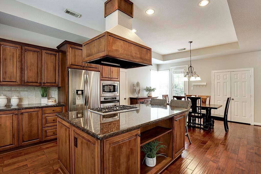 The kitchen boasts stainless steel appliances, gas cooktop, double ovens and granite countertops .