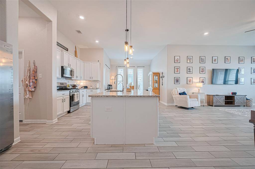 Modern kitchen with granite countertops, a beautiful island, pendant lighting, and open sightlines to the living area-perfect for cooking and entertaining.
