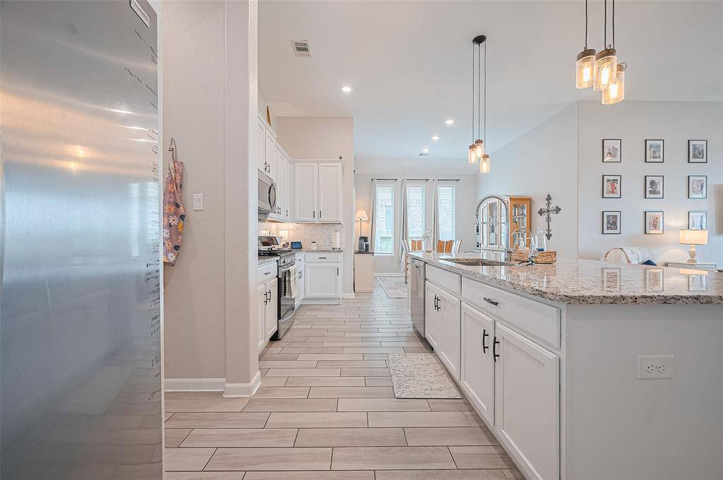 A different angle of this kitchen portrays it's stylish and functional features, such as polished granite surfaces, contemporary pendant fixtures, and expansive cabinetry. The concept design creates an open transition to the adjacent gathering spaces, ideal for everyday comfort.