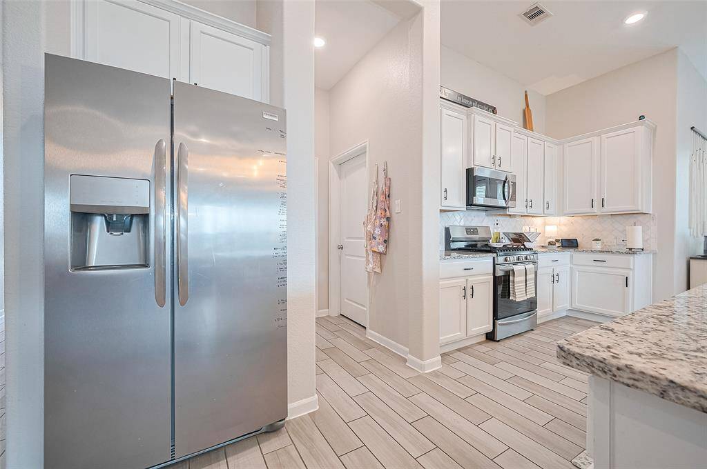 Sleek stainless-steel appliances complement the crisp white cabinetry and granite counters in this modern kitchen. The layout offers both functionality and flow.
