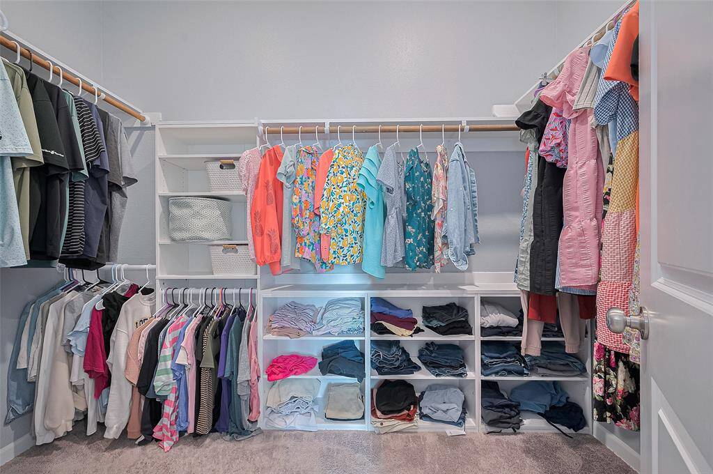 Expansive walk-in closet features custom built-ins and generous hanging space, offering a well-organized solution for storage. The layout maximizes functionality while maintaining a clean, open feel.