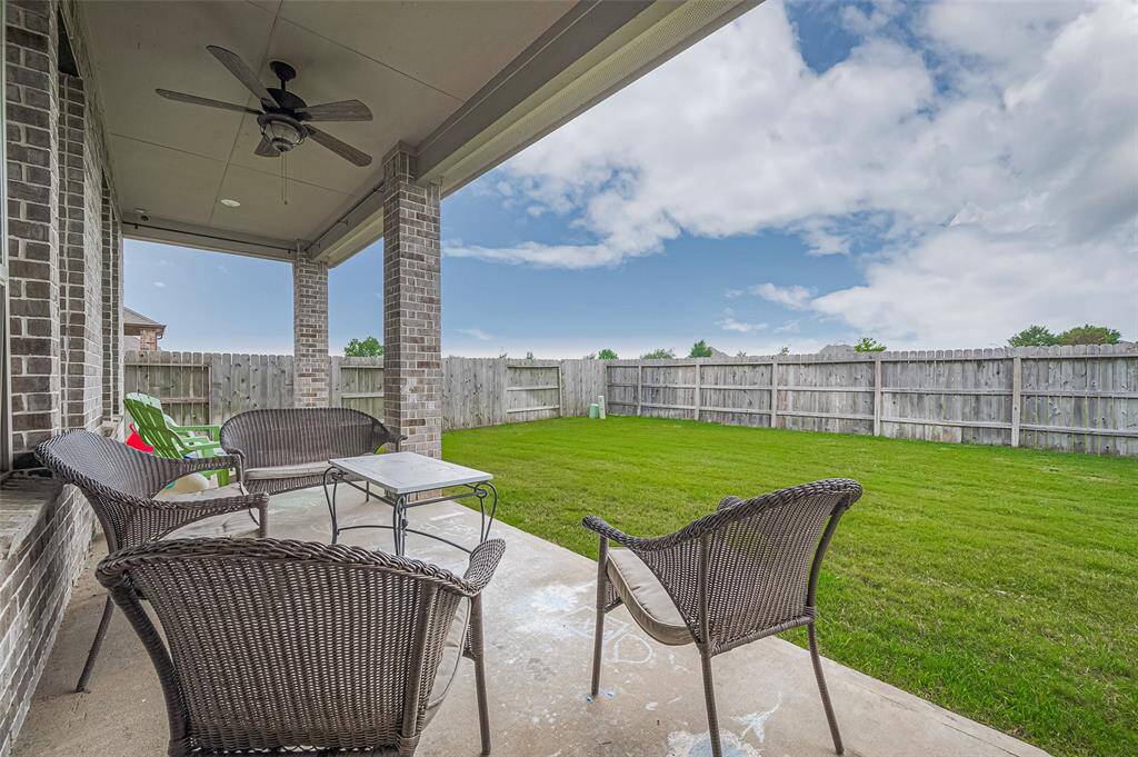 Covered patio offers a relaxing outdoor retreat with ample seating space and a ceiling fan for added comfort. The spacious backyard provides privacy and room to entertain or play.