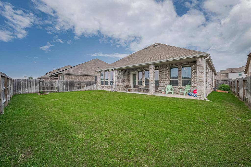 A different angle of this expansive backyard shows the lush green lawn, and the extended covered patio provides a shaded space for relaxing.