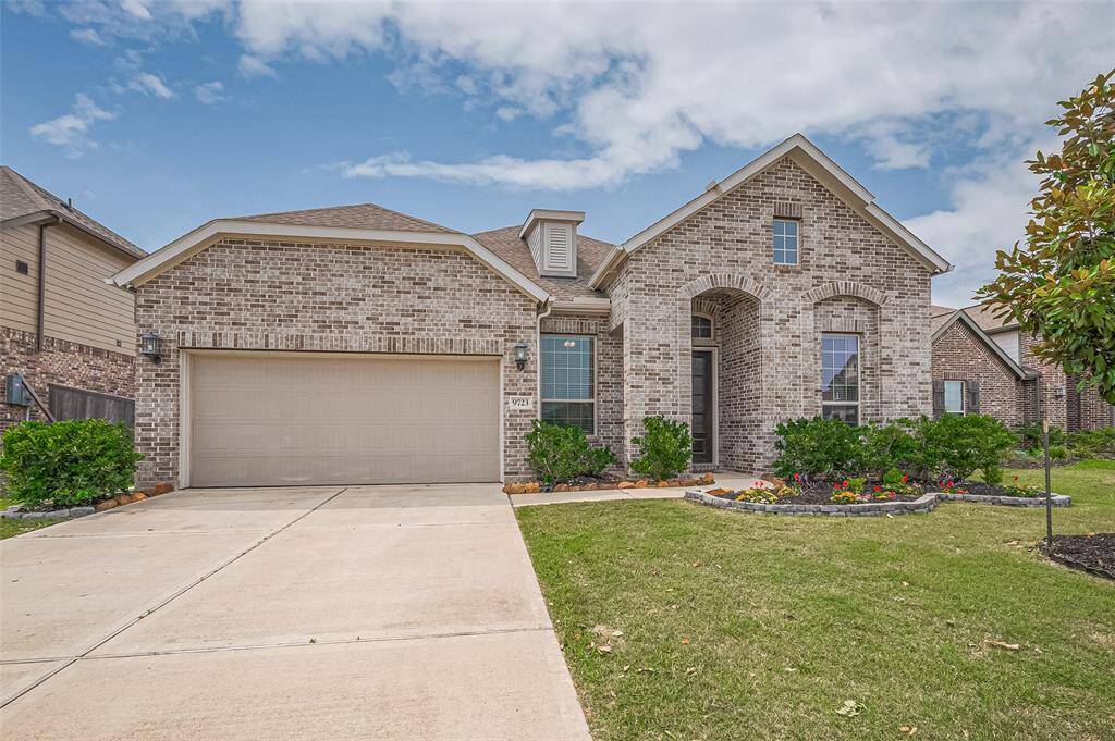 Attractive brick exterior with a welcoming arched entry and manicured landscaping. The wide driveway leads to a two-car garage, enhancing appeal and functionality.