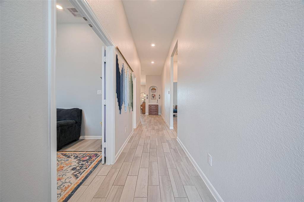 An extended foyer with elegant wood-look tile flooring leads seamlessly into the main living areas. Off the entry, double doors open to a versatile office or study, ideal for working from home or enjoying quiet time.
