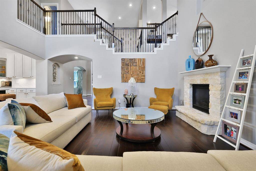 Spacious living room with soaring ceilings, a cozy stone fireplace, and elegant open staircase