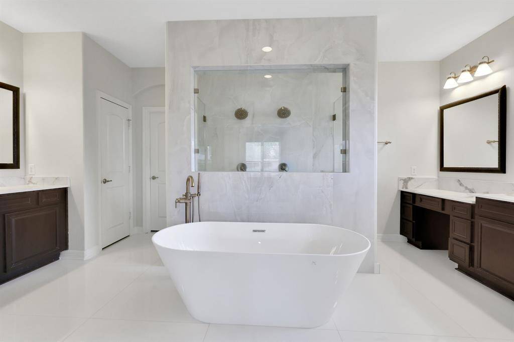 Luxury bath with freestanding tub, dual vanities, and a large walk-through shower