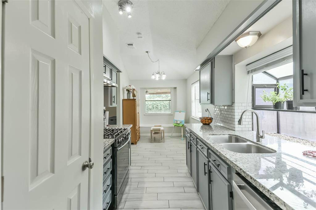 The galley kitchen with stainless appliances is adjacent to a breakfast room with a window seat.