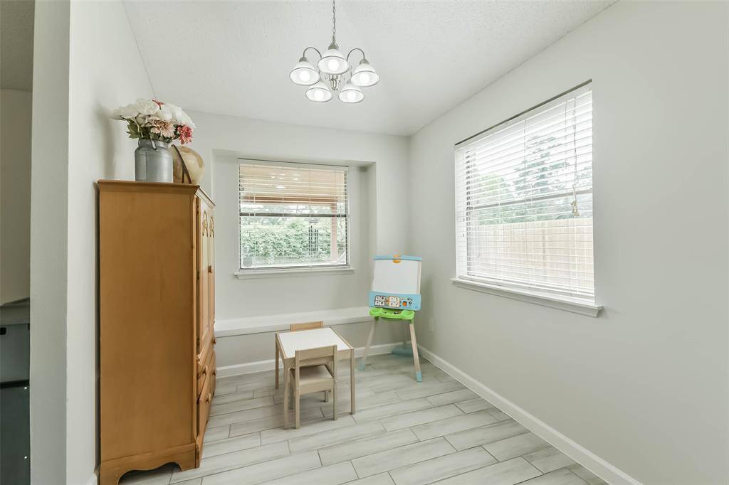 Light and bright breakfast room with window seat, chandelier, and wood look tile.
