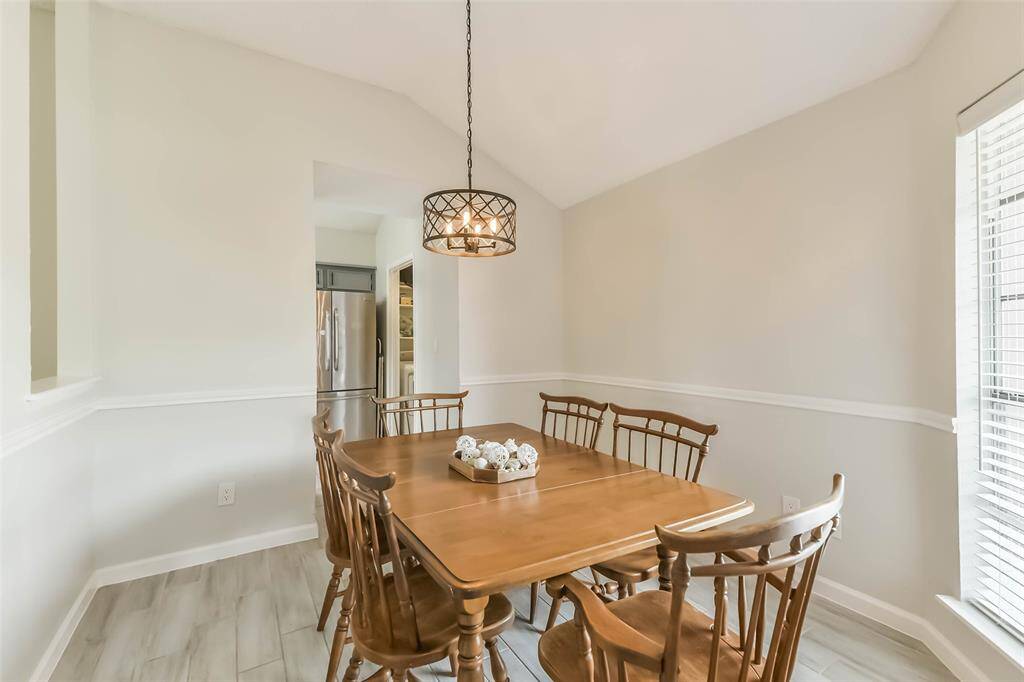Formal dining room with its chair rail, updated light fixture, and wood look tile is easily accessible from the kitchen.
