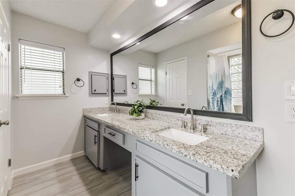 Primary bath has granite counters, updated fixtures, framed mirror, double sinks, medicine cabinet, and a vanity space.
