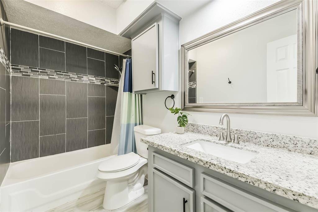 Updated hall bath with designer tile tub surround, granite counters, updated fixtures, and framed mirror.