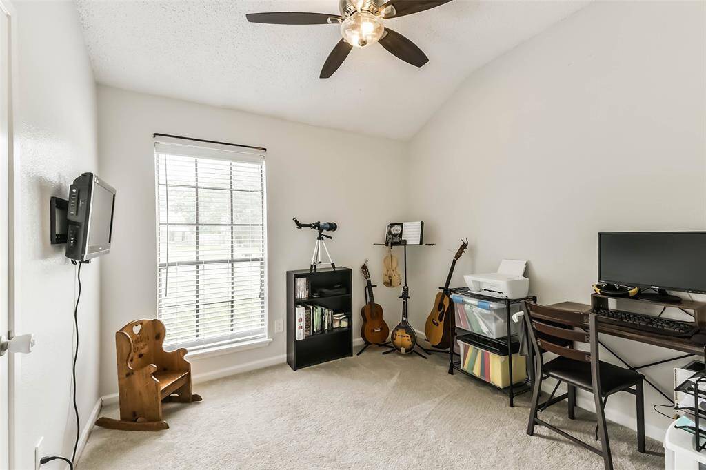 Bedroom three with ceiling fan and TV mount being used as a study and music room.