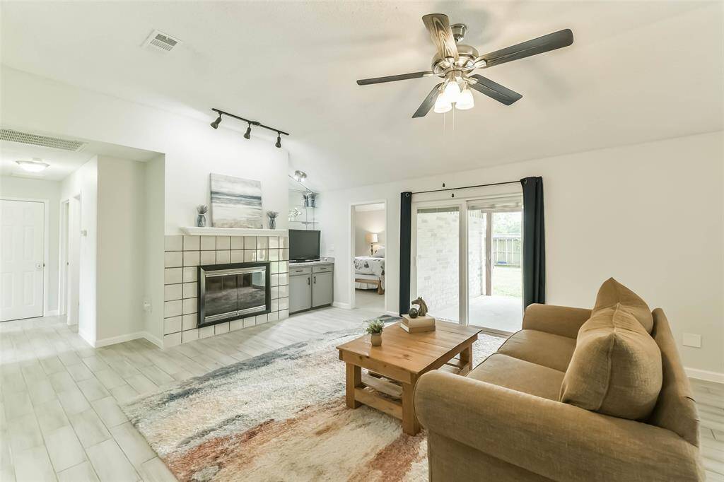 Built-in cabinets, gaslog fireplace, updated sliding glass doors with interior blinds, and a ceiling fan highlight this generous sized living area with wood look tile.