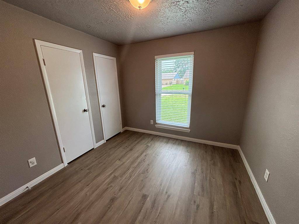 This cozy bedroom features sleek flooring, ample natural light from a large window, and convenient closet space, creating a perfect retreat.
