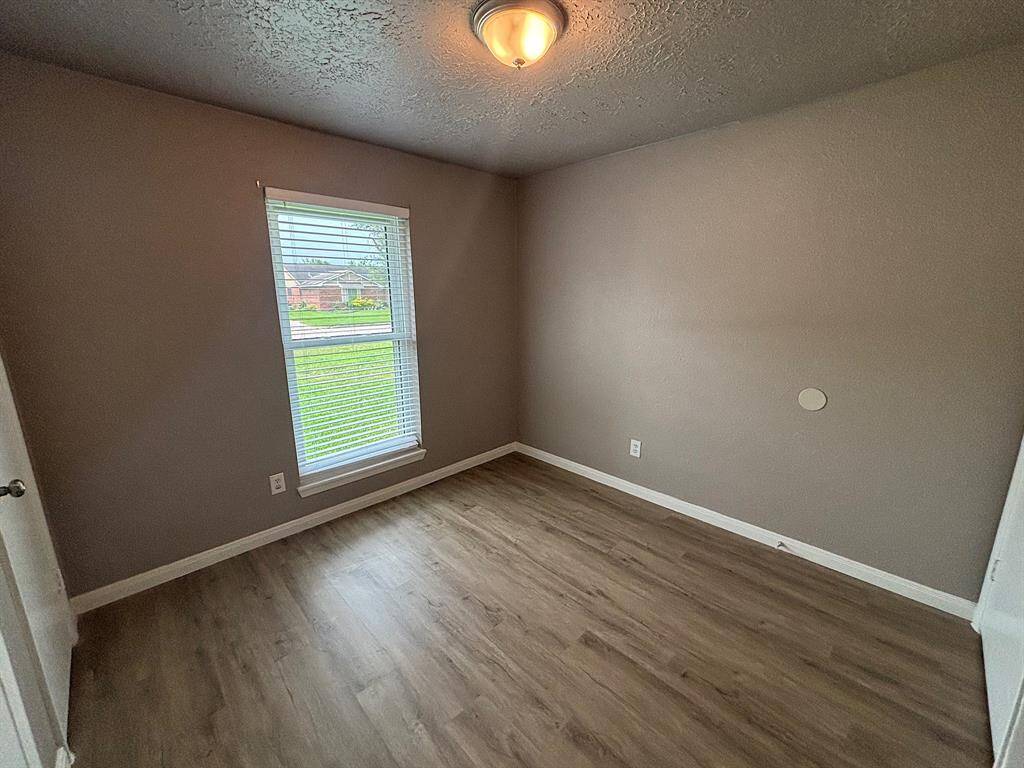 Bright secondary bedroom with elegant wood floors and a neutral palette, ideal for personal touches.