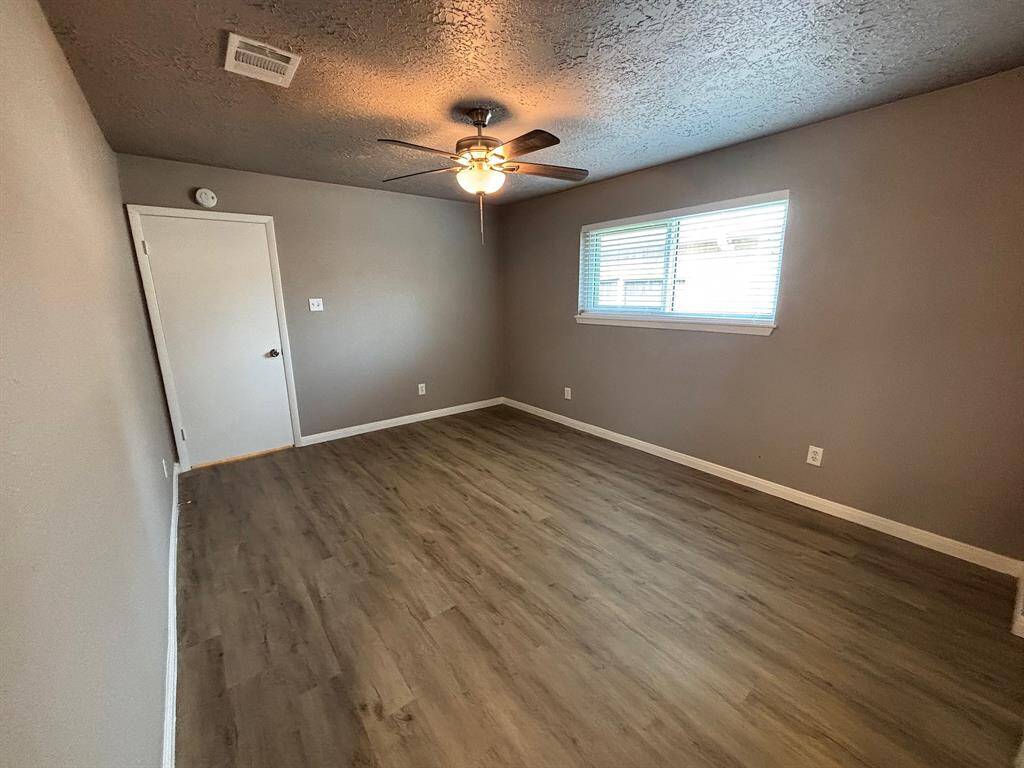 Spacious primary bedroom featuring modern flooring, ample natural light, and a ceiling fan for comfort.