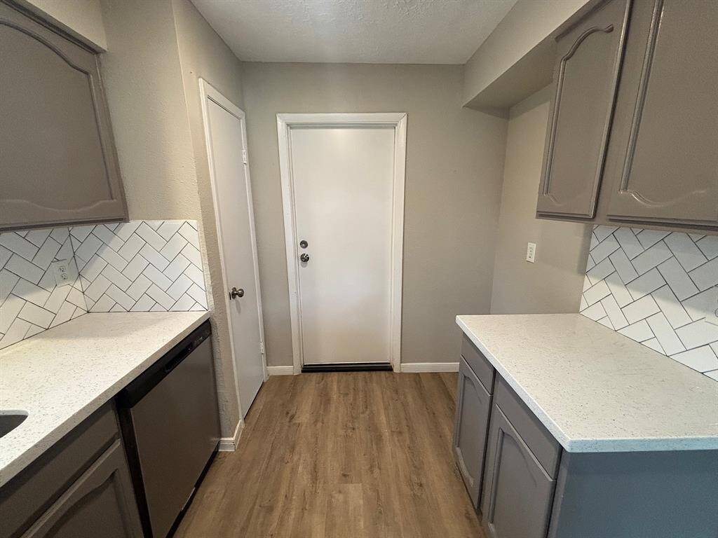 This kitchen features a stylish neutral palette, elegant wood-style flooring, and a convenient dishwasher.