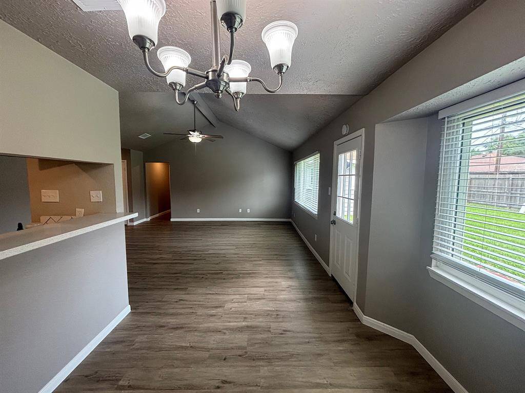 This photo showcases a bright, open-concept living space with modern light fixtures, neutral walls, and wood-style flooring.