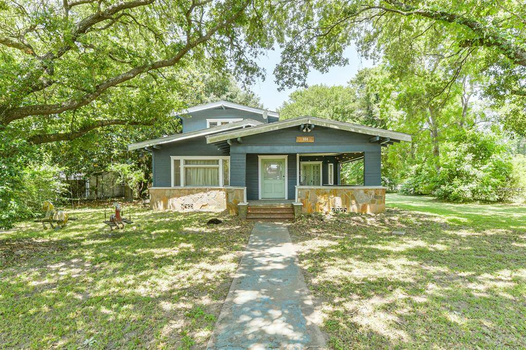Charming Craftsman-style home with a welcoming front porch, set amidst lush greenery. Features a spacious yard and beautiful mature trees, offering ample shade and a serene atmosphere.