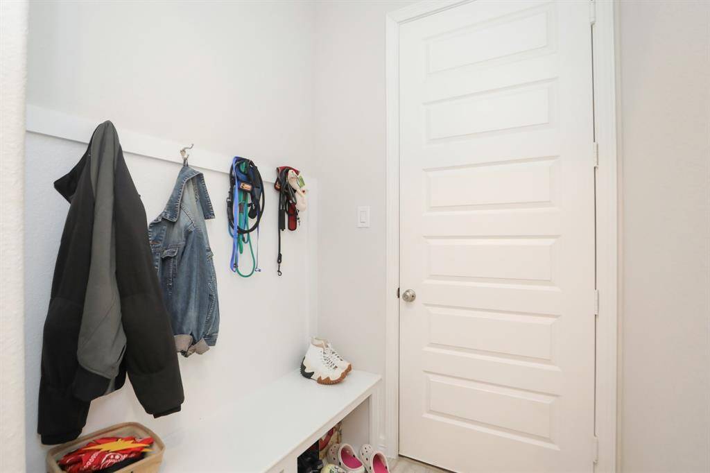 Mud room located by the garage with a bench and storage.