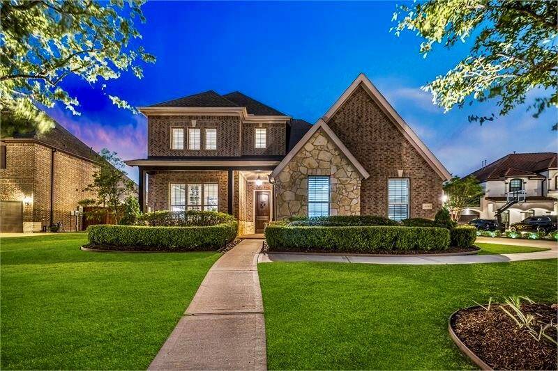 Beautifully maintained brick and stone home features stunning curb appeal, manicured landscaping, and a welcoming front entryway.