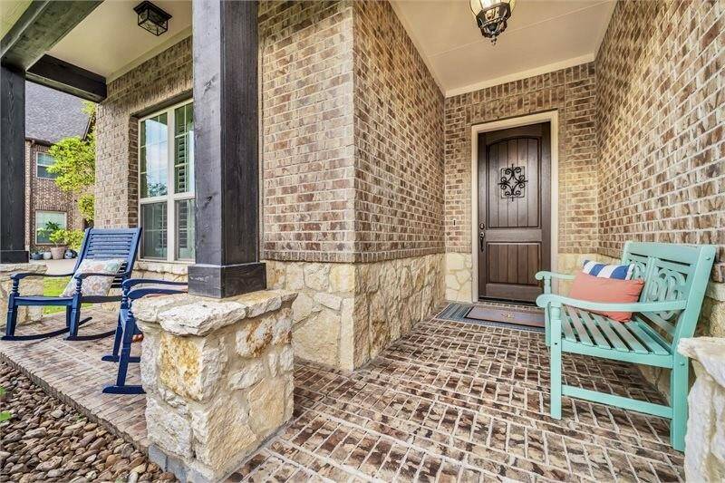 Charming covered front porch features an inviting seating area, classic brick and stone accents, and a welcoming entryway perfect for relaxing or greeting guests.