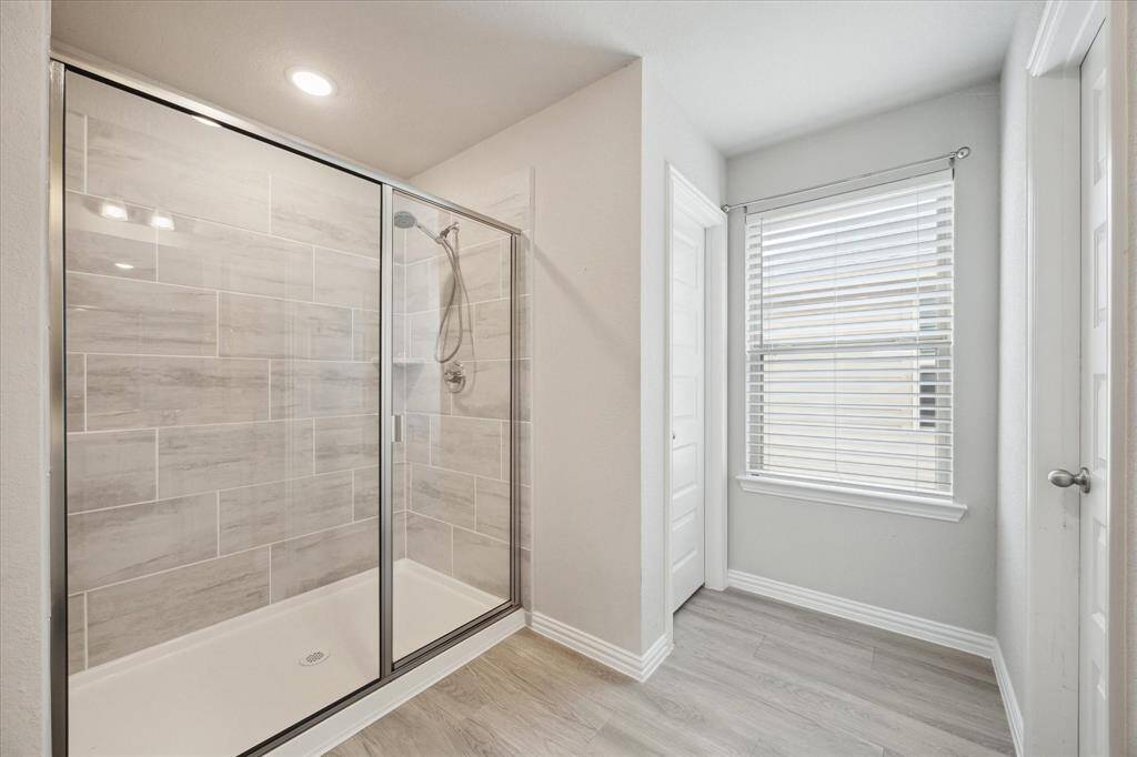 THE PRIMARY WALK-IN SHOWER WITH TILE SURROUND.