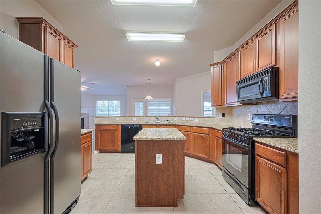Warm wood cabinetry pairs beautifully with granite countertops, while the central island offers function and form. The raised bar subtly separates the kitchen from adjacent spaces without closing them off.