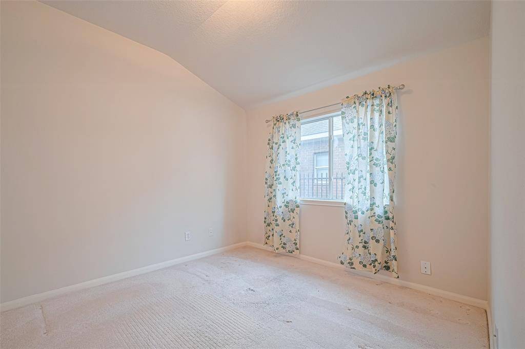 Soft carpet underfoot and a gently sloping ceiling lend this bedroom a tranquil tone, while the large window draws in natural light that shifts with the day.