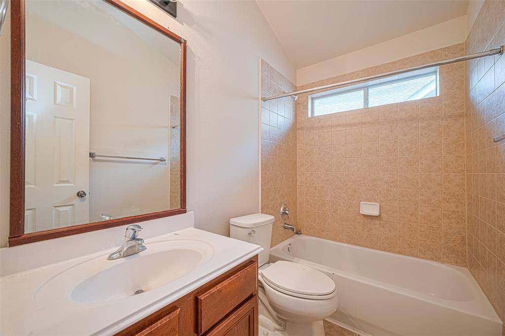 A well-lit full bath features a combined tub and shower, a single-sink vanity, and a window that adds a touch of warmth to the clean functionality.