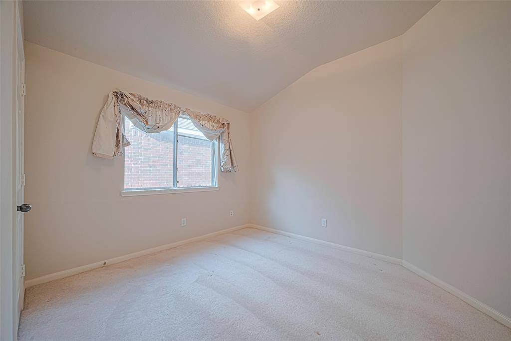 Bright and restful, this additional bedroom echoes the home's welcoming palette and includes a large window that looks out onto the yard beyond.