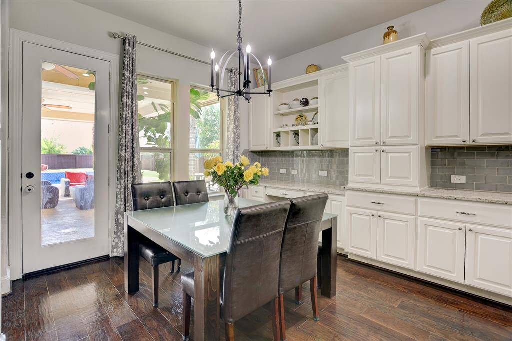 A stylish kitchen features white cabinetry, a glass-tile backsplash, and modern lighting. Hardwood floors and French doors offer poolside views and indoor-outdoor flow.