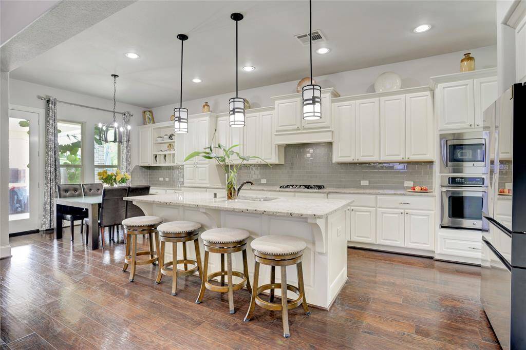 Sleek and spacious, this kitchen offers a large island with seating, pendant lights, and stainless steel appliances. An open layout connects to a bright dining area, ideal for hosting.