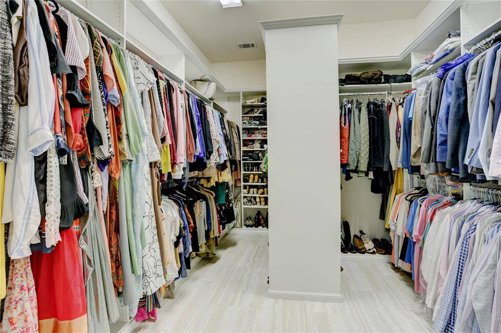 A spacious walk-in closet with built-in shelving and hanging space offers generous storage. The room is well-lit and neatly organized for everyday ease.
