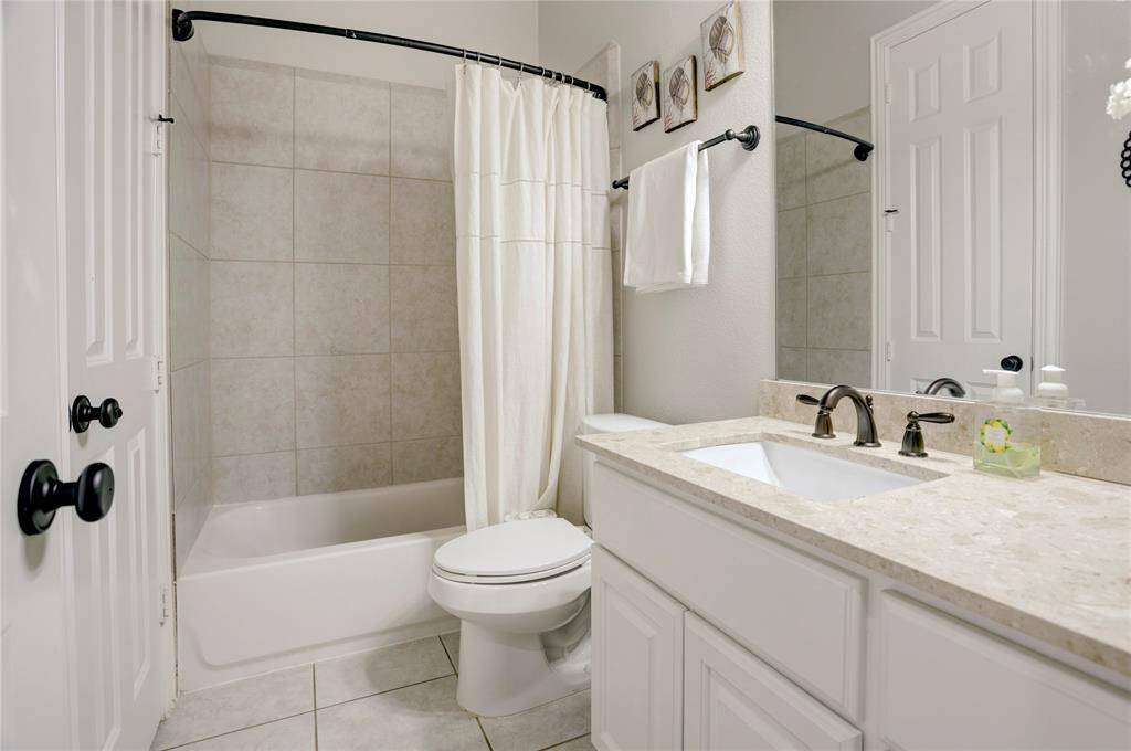 A functional and stylish bathroom with a tiled shower-tub combo, modern sink, and sleek neutral tones—perfect for daily use or guest convenience.