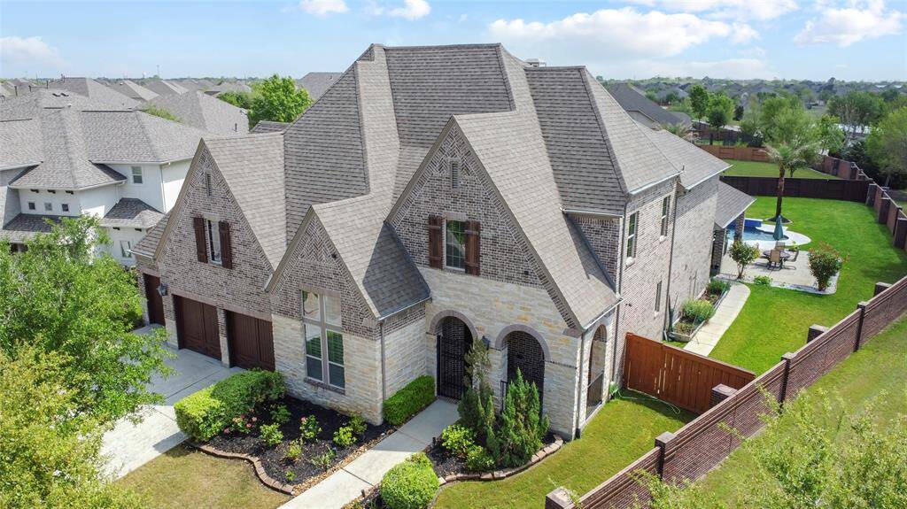 Classic elegance shines through this two-story brick and stone residence, surrounded by manicured landscaping. A large backyard with a paved patio provides space for gatherings, all nestled in a peaceful community of well-kept homes.