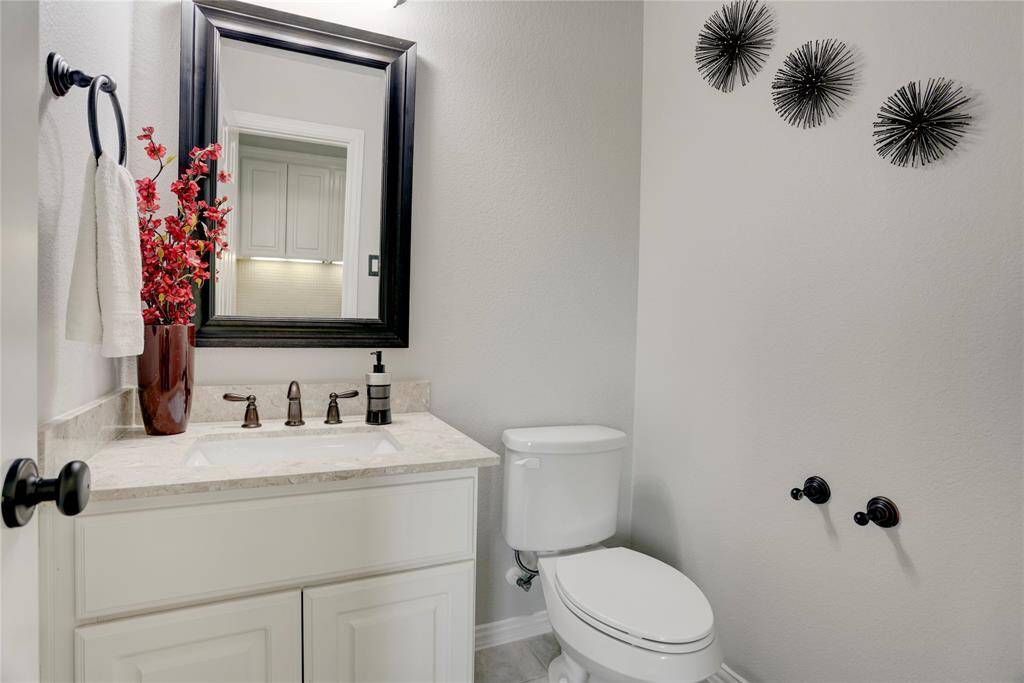 A clean and modern bathroom featuring a marble-topped vanity, large mirror, and stylish fixtures. Bold accents like red flowers add a pop of personality.