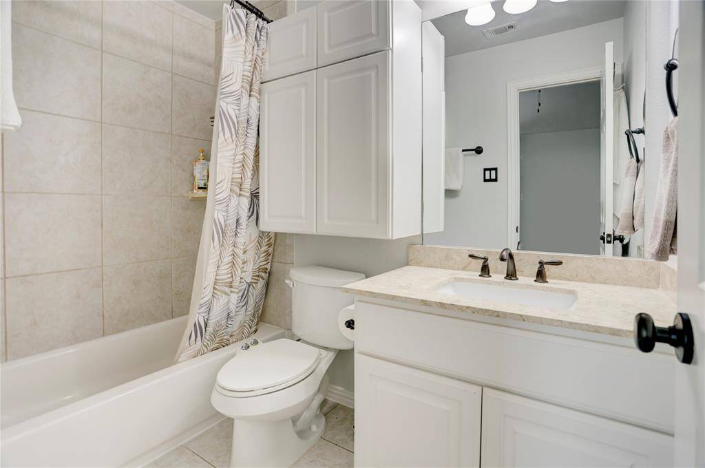 A bright bathroom with a clean design includes a tiled shower/tub, sleek white vanity, and soft lighting—perfect for everyday routines.