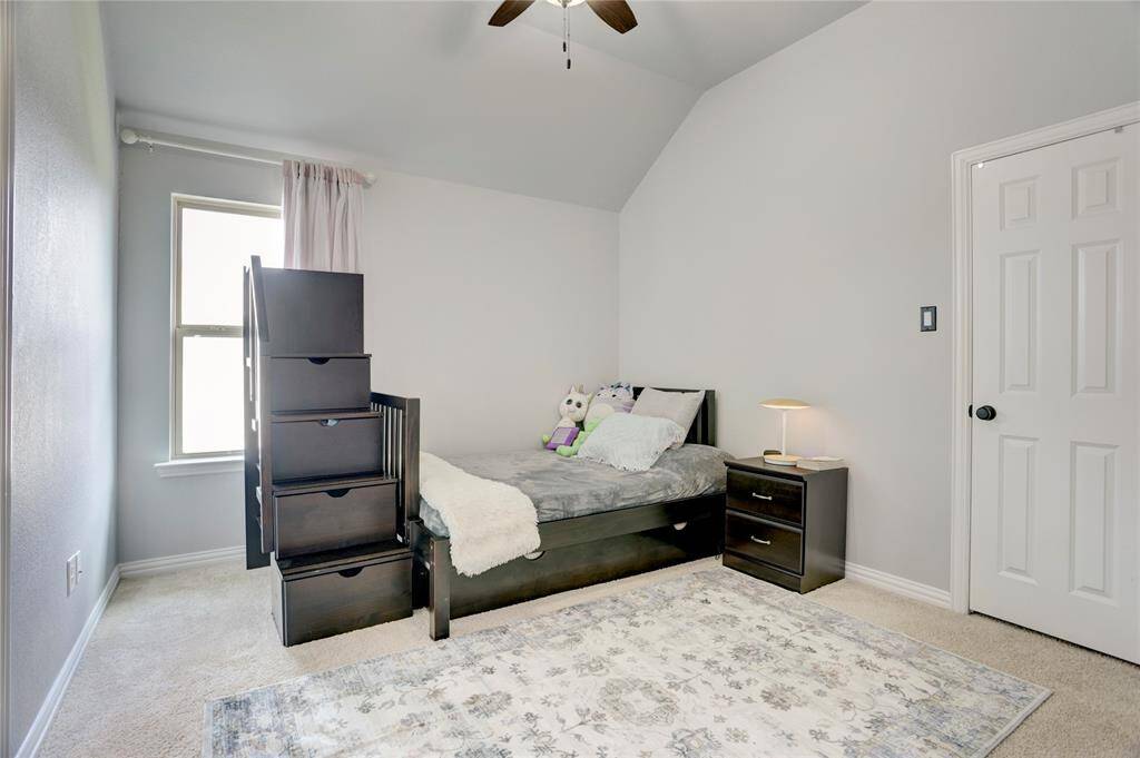 A cozy child’s room featuring a single bed, soft carpet, large window with curtains, and charming furnishings in soft, neutral tones.